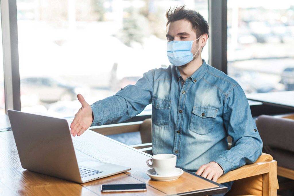 Man in Mask Reaching Out to Laptop