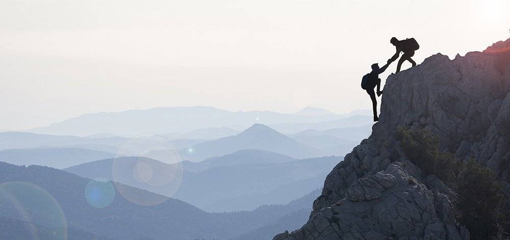 Two Climbers Helping Each Other to the Top
